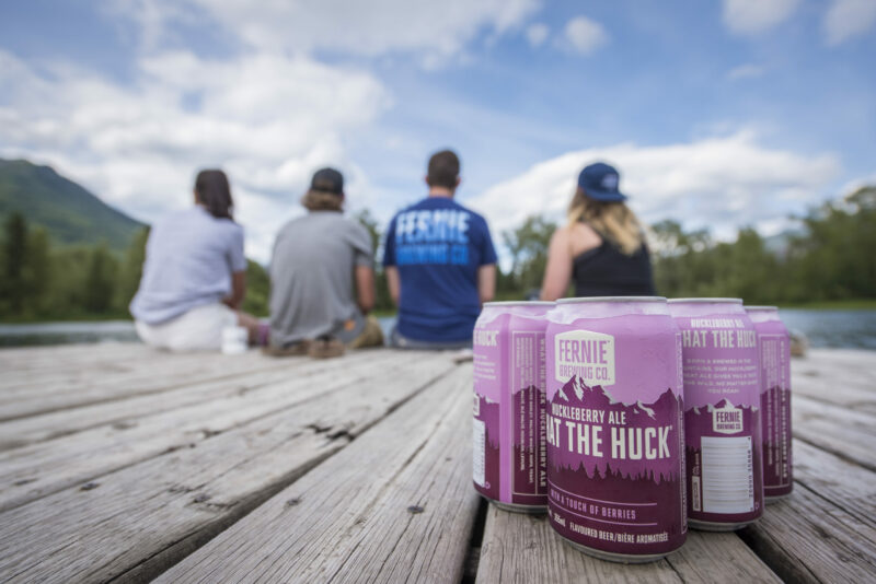 6-pack of What the Huck Huckleberry ale on a dock at Maiden Lake Fernie BC