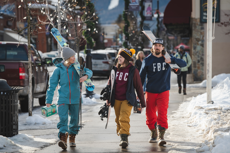 Skiers and snowboarders walking in downtown Fernie BC in FBC gear.