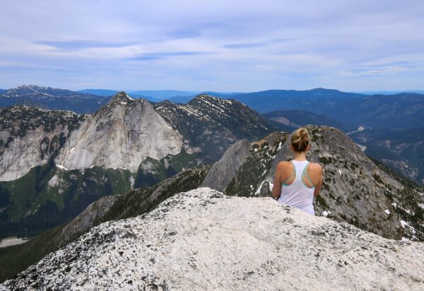 Woman sat on top of mountain looking at view.