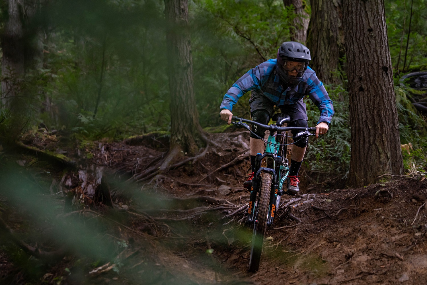 Micah mountain biking down a rooty path