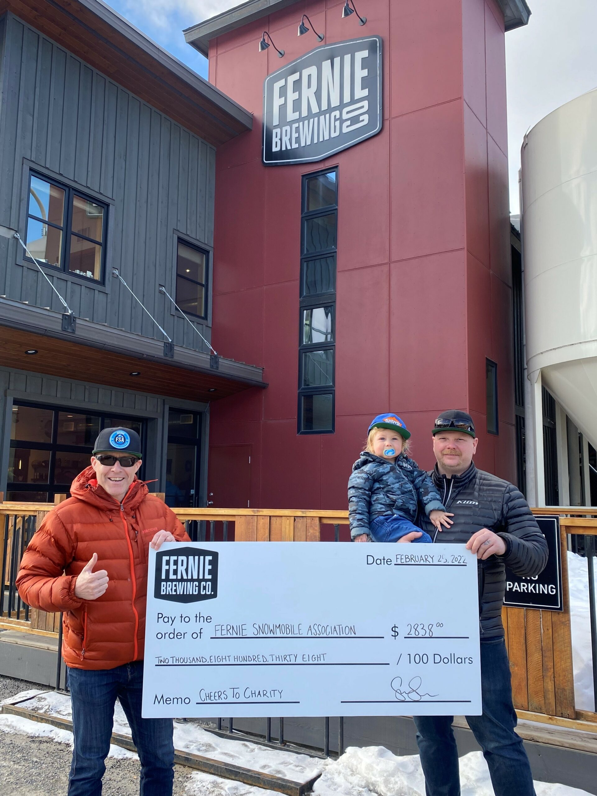 the Fernie snowmobile club accepts a donation cheque in front of the Brewery