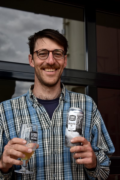 jack smiling holding a can and glass full of kolsch