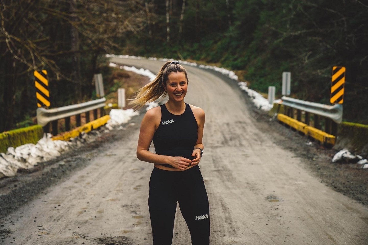 A woman in running clothes standing on a bridge