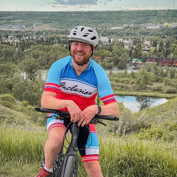 A man on his bike on top of a hill overlooking a suburb