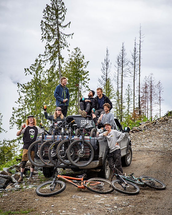 a group of people hanging out on the back of a truck with bikes in the back