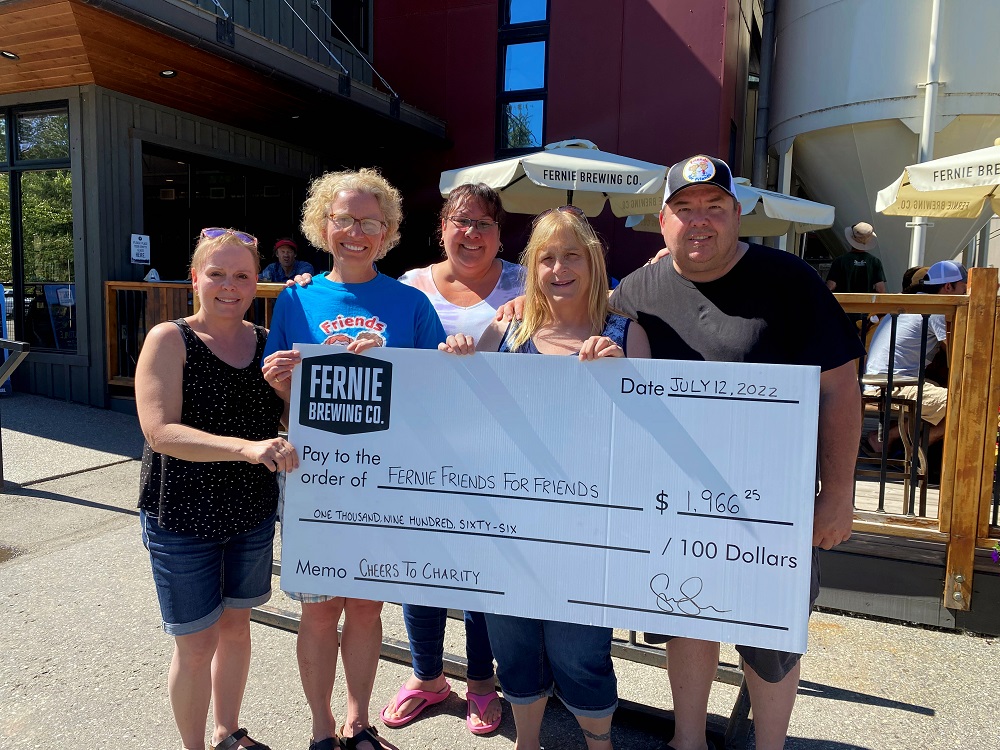 5 poeple holding up a large donation cheque