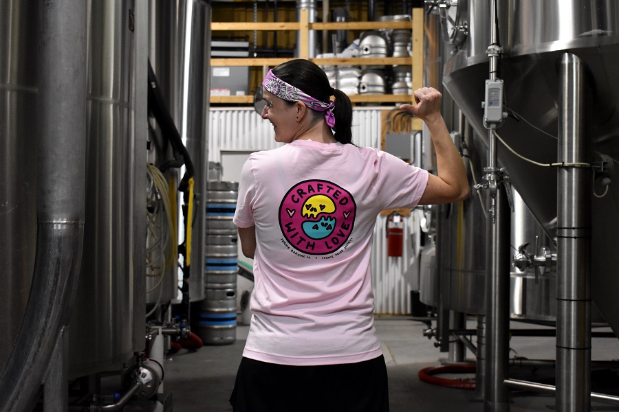 Woman in a brewery pointing to the back of her shirt