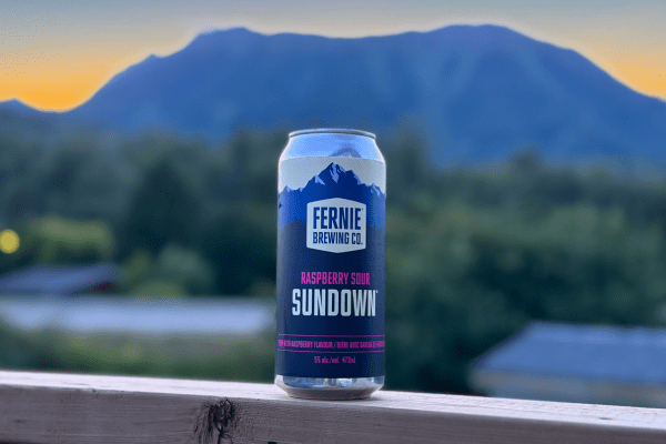 A can of Sundown Raspberry Sour at sunset with a mountain in the background