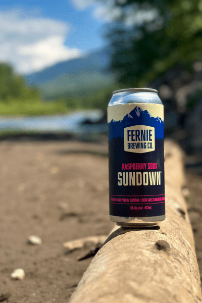 A can of Sundown Raspberry Sour on a log by a river