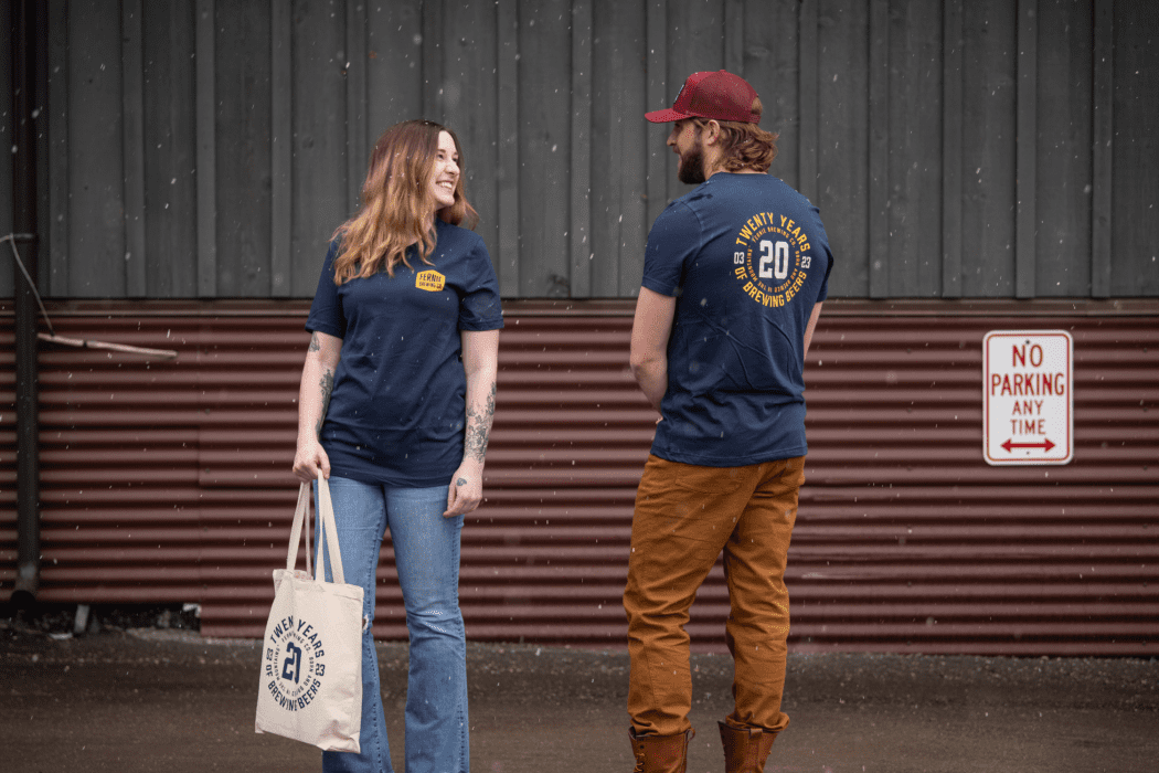 A man and a woman wearing matching FBC 20th Anniversary t-shirts looking at one another.